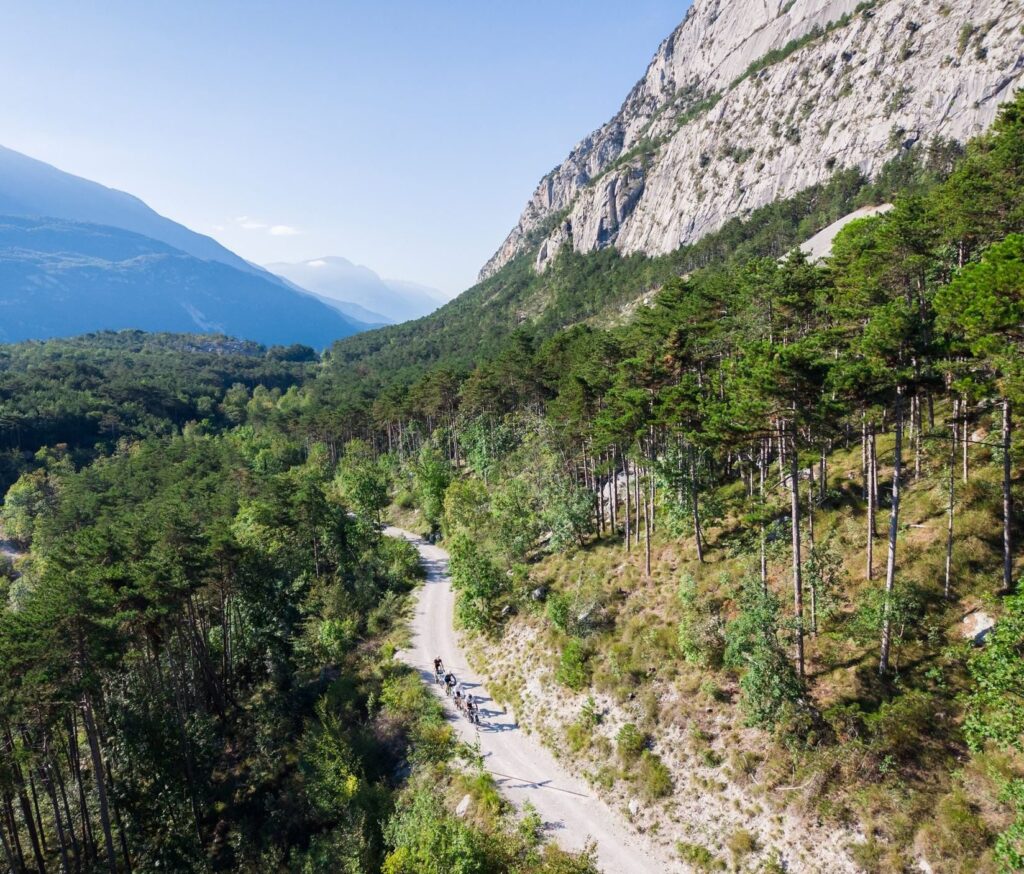 A gravel road crosses a green valley under high rock walls